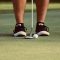 Golfer putting: putter and golf ball near feet