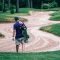 Golfer carrying bag walking through winding sand bunker